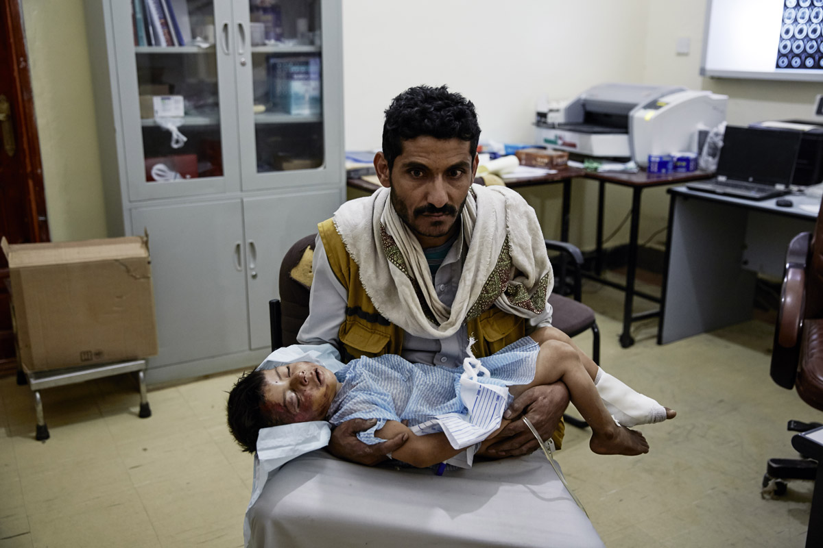 空爆で負傷した息子を抱える父親。2016年イエメンにて（©MSF）