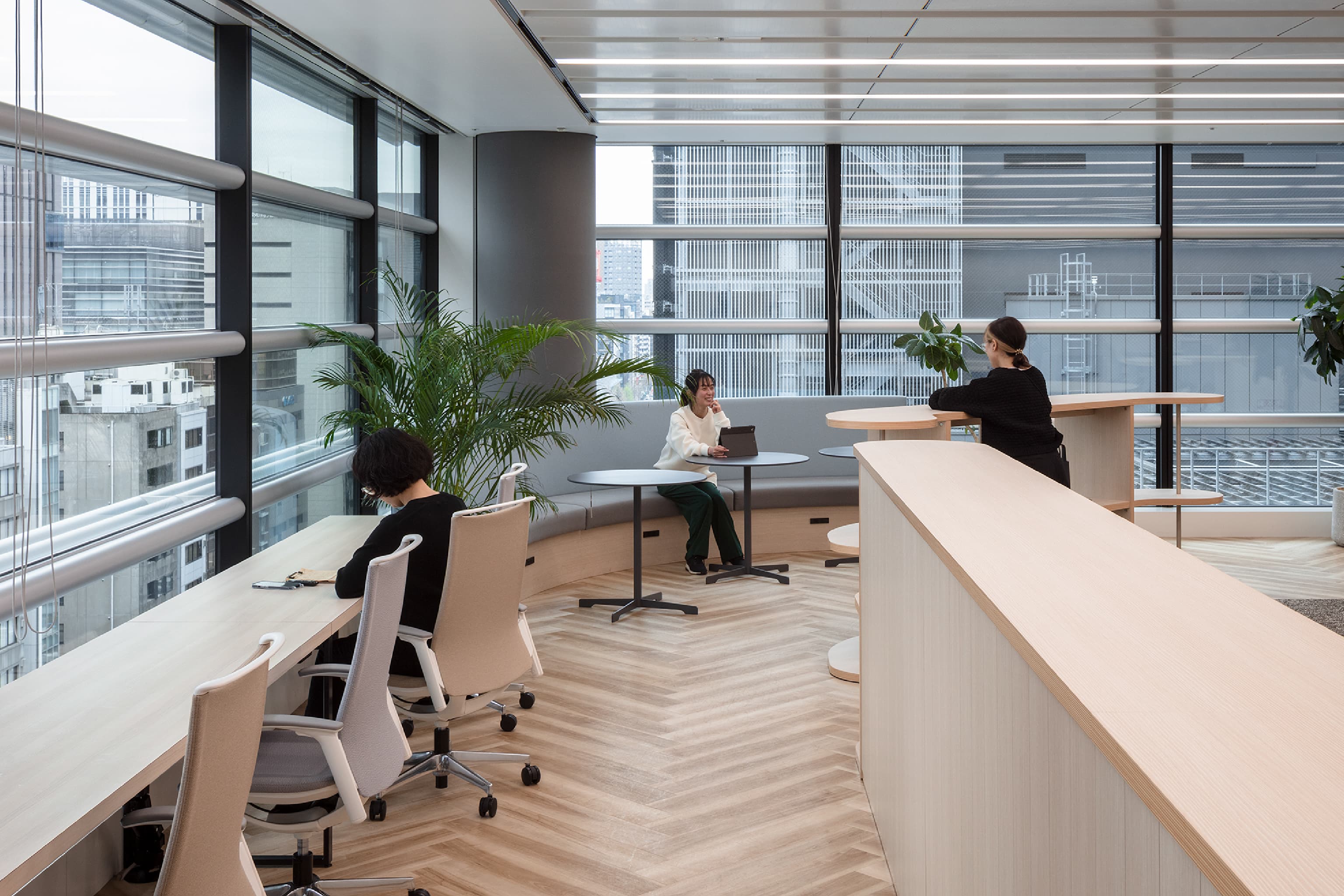 株式会社アイネス 様の事例写真／[執務エリア]他拠点社員向けのサテライトエリアには、カウンター席やソファ席などが設けられています。執務エリアの動線も兼ねているため、通りかかった社員との雑談が始まることも