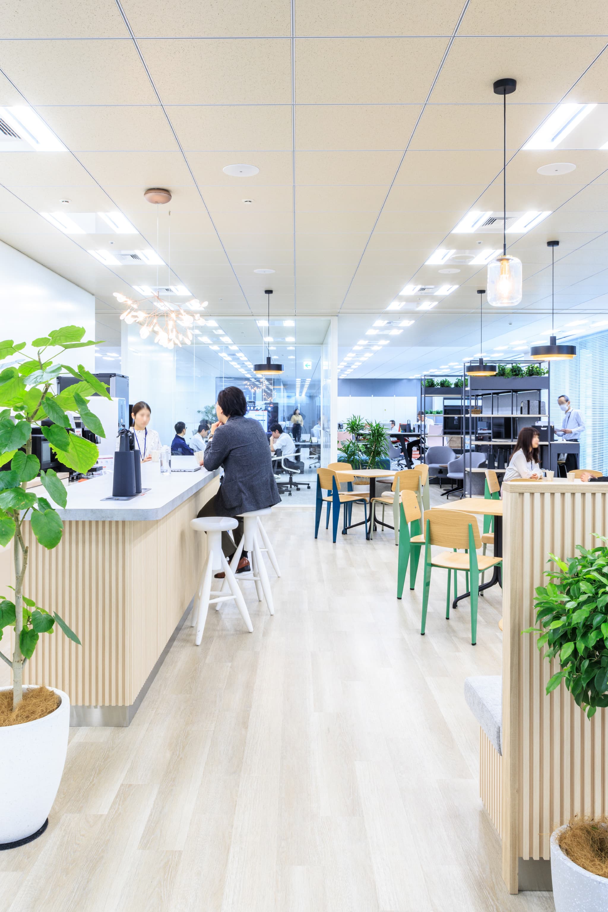 関西ペイント株式会社 様の事例写真／[カフェエリア]カフェエリアのカウンターでは、顔を突き合わせて会話を楽しむメンバーが。話の輪の中に入りやすいシチュエーションは、偶発的な出会いやコミュニケーションを生み、新たなアイデアが生まれるでしょう。