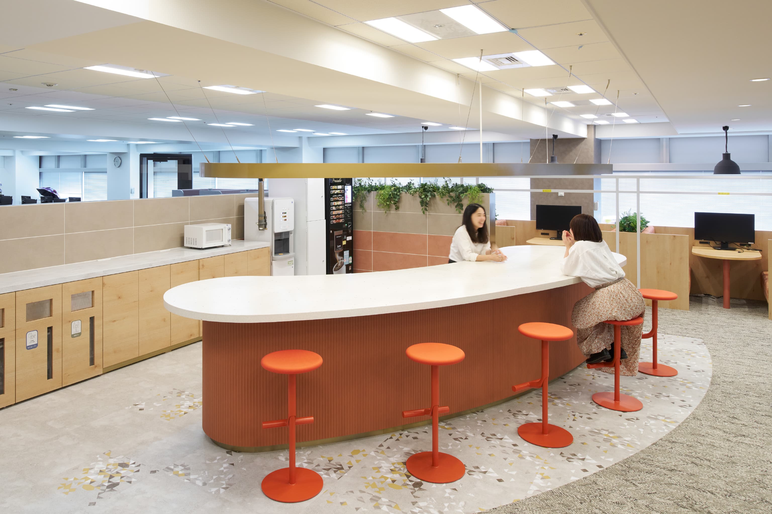 IQVIA ジャパン グループ 様の事例写真／[共創空間（5階STAGEエリア）]アーチ状のカフェカウンターは、みんなが集う象徴的な場所。その奥にはモニター付きのファミレスブースがあり、社内打ち合わせにも活用できます。コーヒーを振る舞う会など、社員同士での交流イベントが開かれることも。