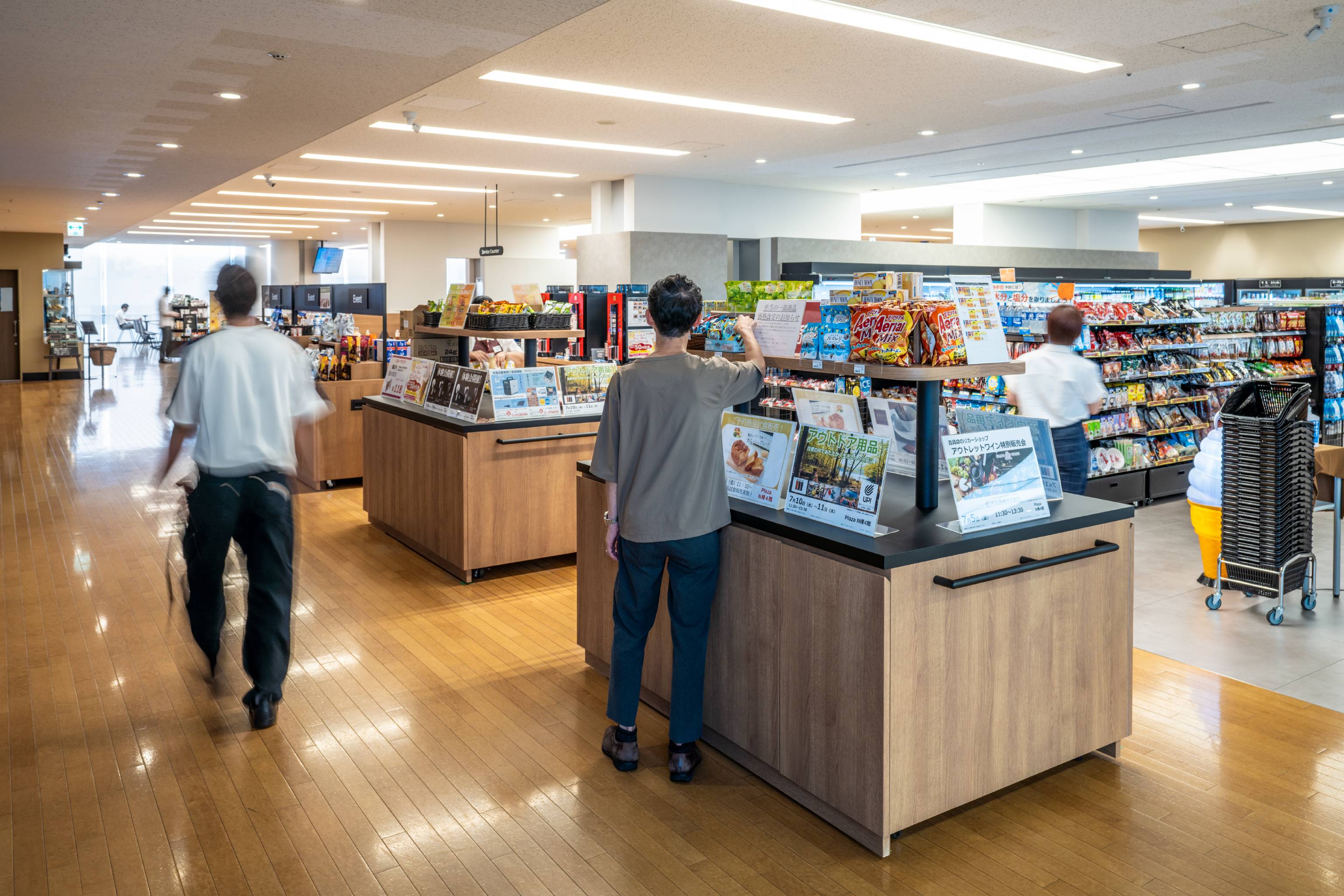 NEC （日本電気株式会社） 様の事例写真／[北棟 売店]食堂フロアの中間地点に配置された売店は、喫食空間とトーンを合わせ、統一感が出されています。終業後にここで飲み物を買い、アペロ（ちょい飲み）を楽しむ社員の姿も。ラフなコミュニケーションに役立っています。