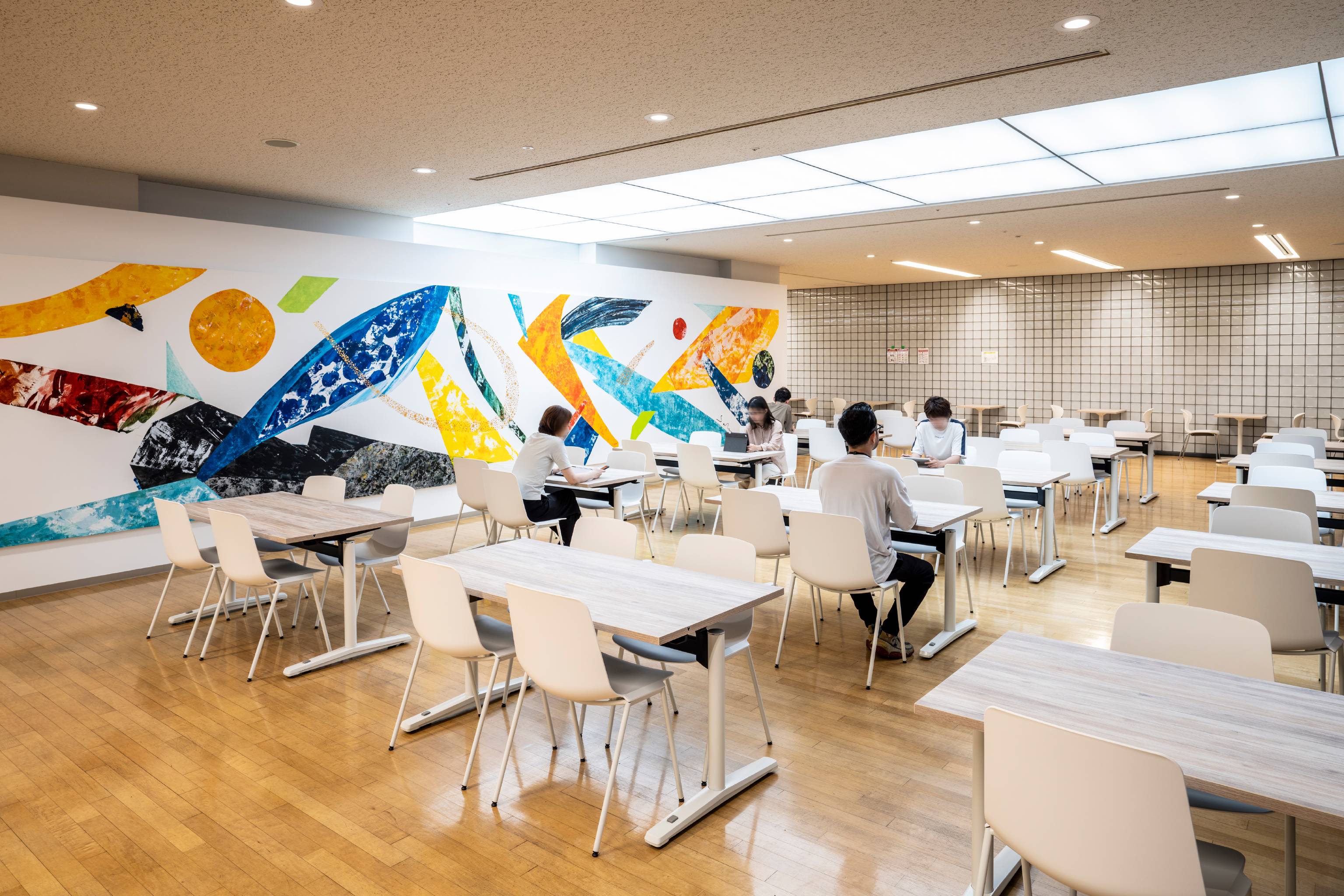 NEC （日本電気株式会社） 様の事例写真／[南棟 ミューラルアート「時空の旅」 田中紗樹]ミューラルアートの制作中は社員とアーティストがその場で絵の方向性について議論したり、アーティストが絵筆を取る様子を休憩中の社員が鑑賞したりしていました。