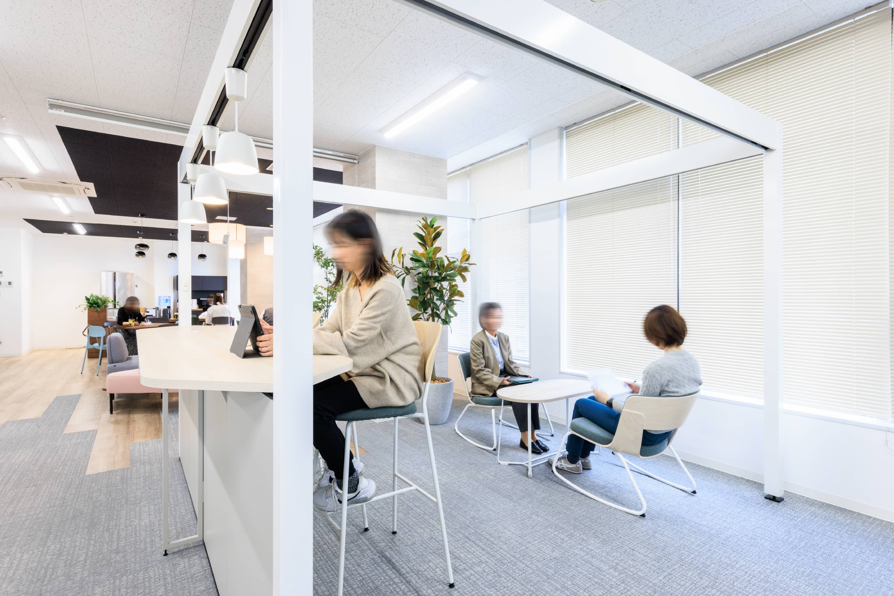 株式会社よーじや 様の事例写真／[カウンター席（執務エリア）]窓際には、ゆらゆら揺れるロッキングチェアを設置。休憩時間に、2人で談笑をして過ごすのにぴったりです。リフレッシュエリア側の天井にはロールカーテンが設置され、空間を簡単に仕切ることができます。
