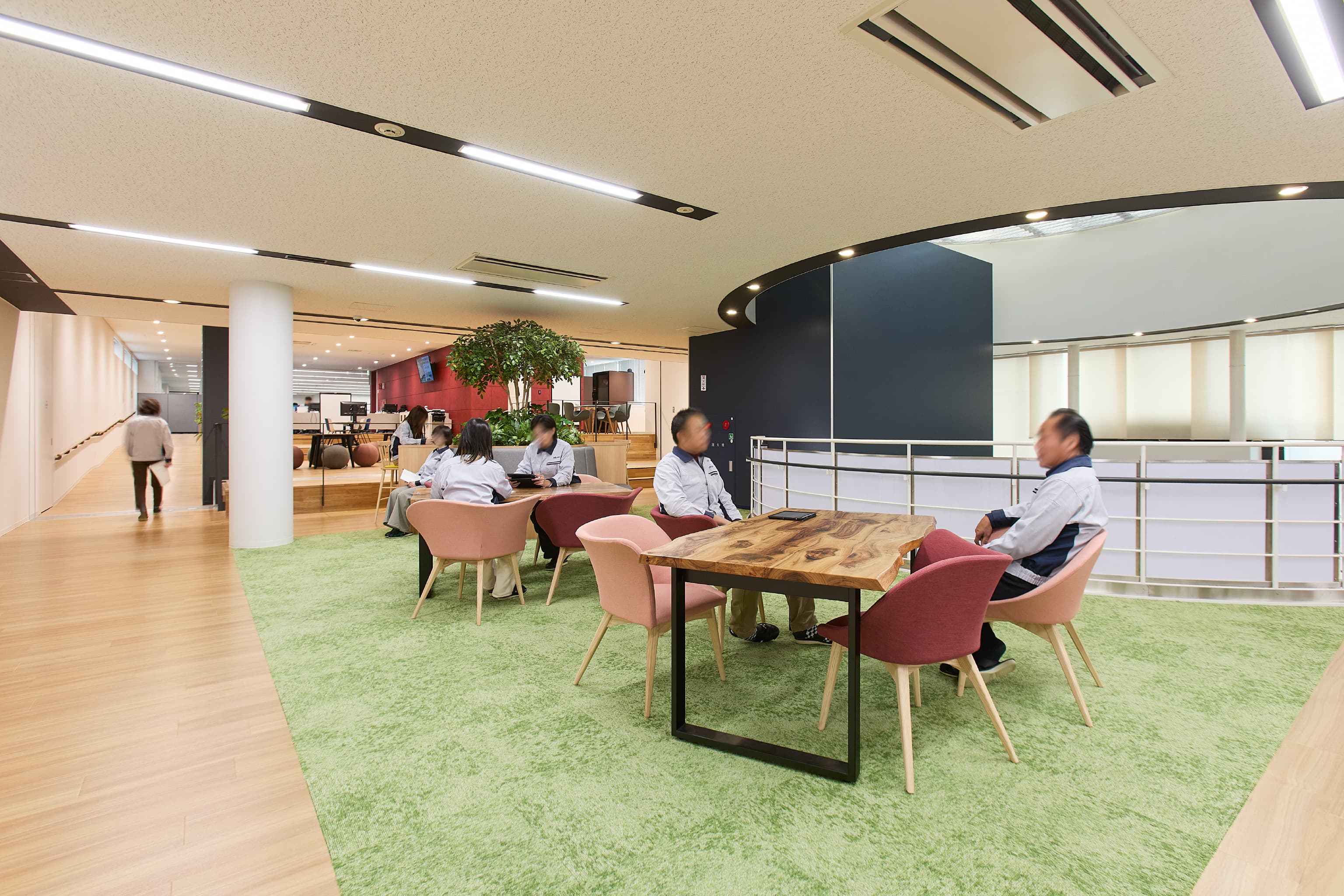 日東電工株式会社 様の事例写真／[2F Connect（交流エリア）]既存棟と新棟をつなぐスキップフロアには、イスとテーブルがゆったりと配置されています。テーブルは、新棟建設の際に出た伐採木で作ったもの。今ある資源を大切にする姿勢と、木のぬくもりが感じられます。