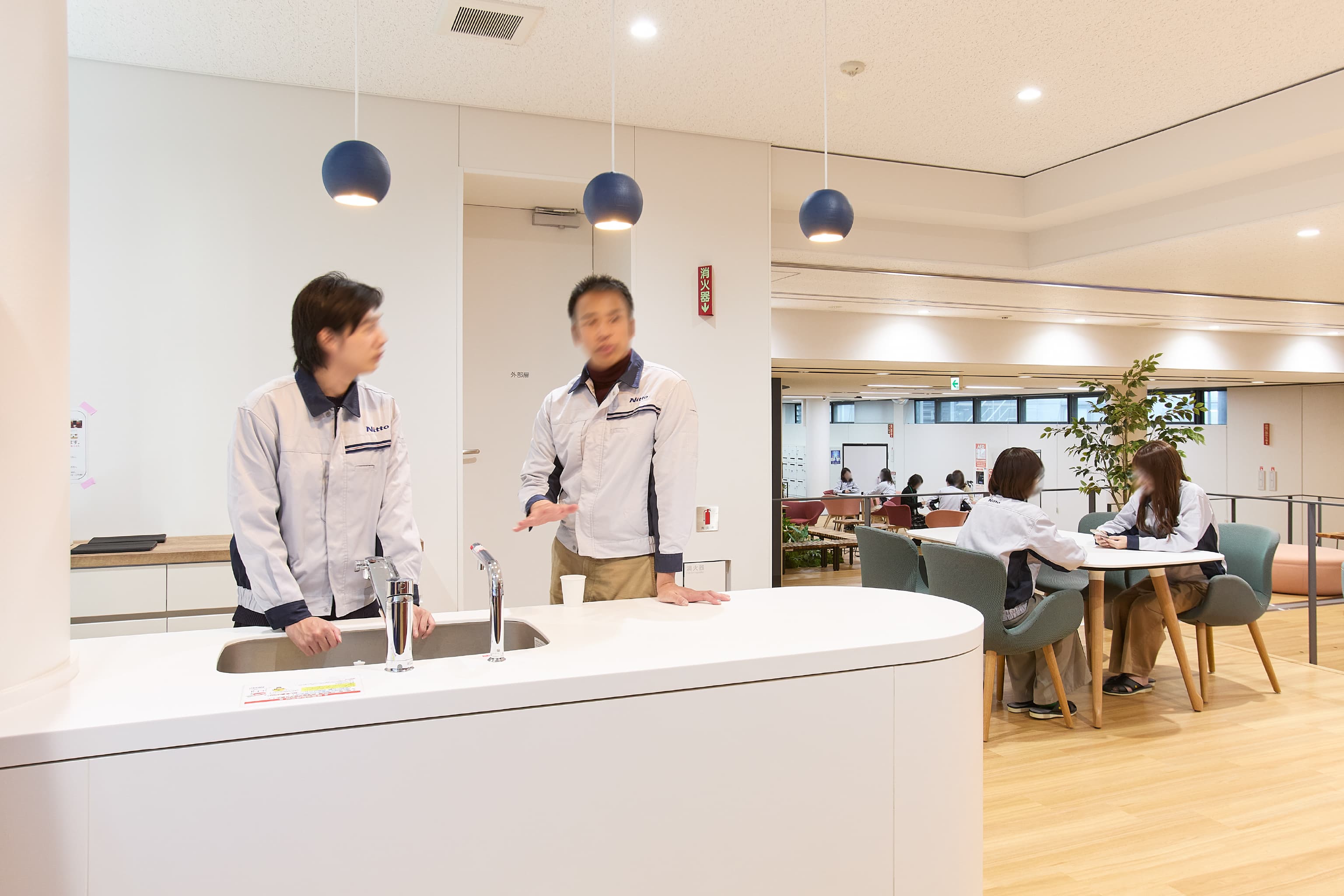 日東電工株式会社 様の事例写真／[2F Connect（交流エリア）]アイランドスタイルのミニキッチンで、弁当箱やコップなどを洗いながら立ち話。給茶機が設置してあり、マイコップを片手に一息つきながら会話が生まれる、オープンな空間となっています。
