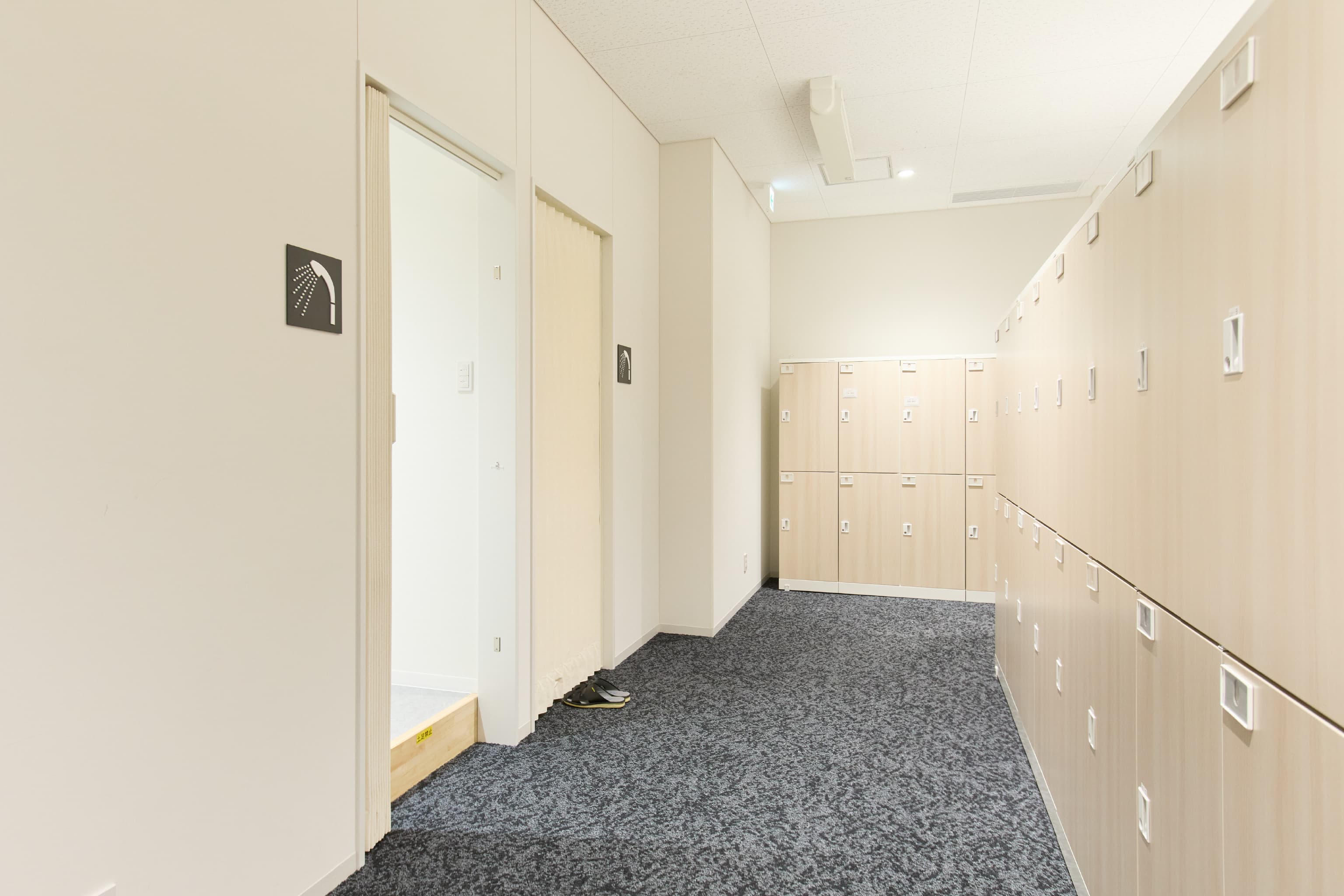日東電工株式会社 様の事例写真／[1F 更衣室]作業を終えた従業員が、着替える前にシャワーを使えるようになりました。私服通勤導入に伴い、さらに働きやすい環境が整備されています。