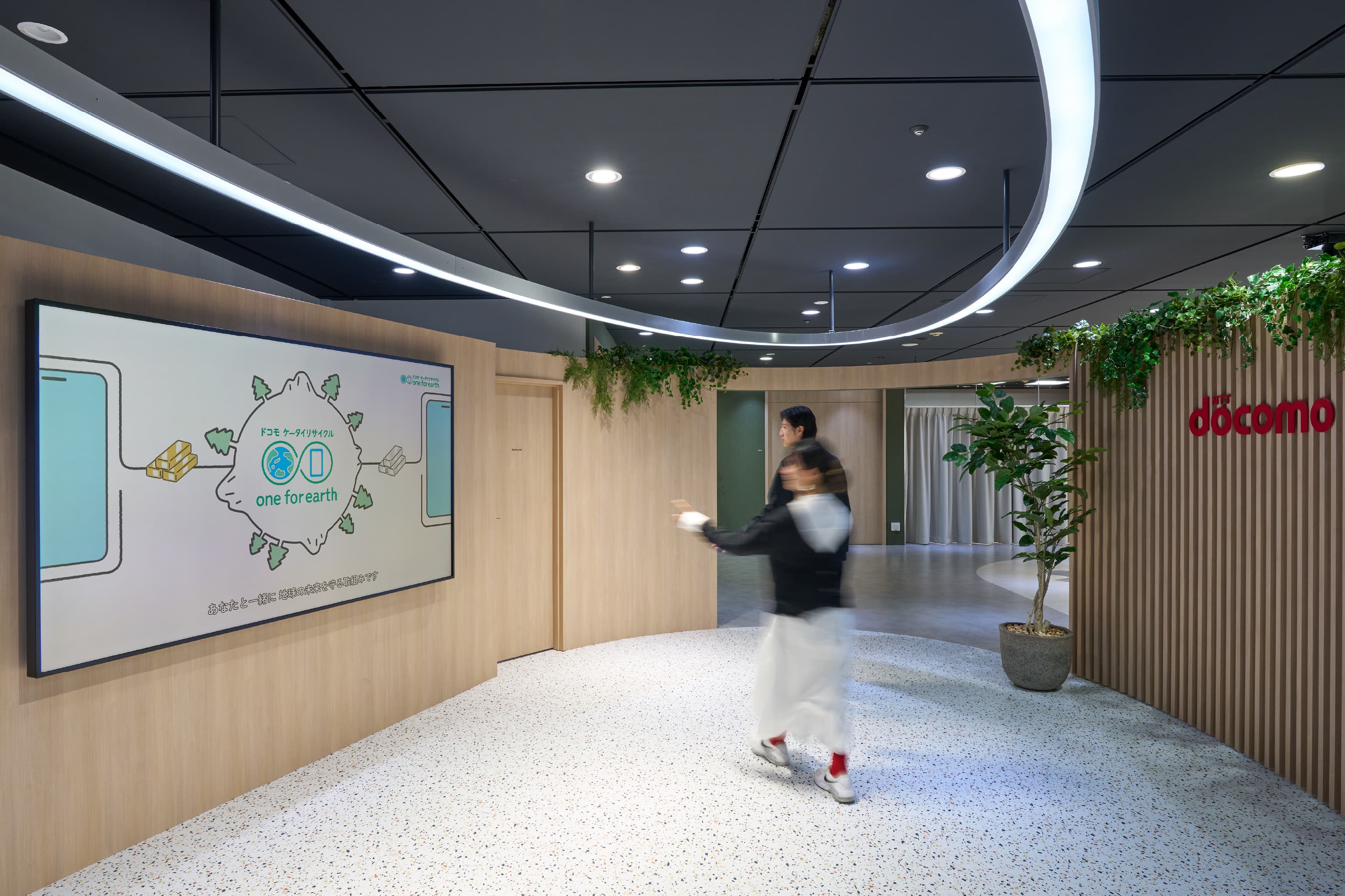 株式会社NTTドコモ 様の事例写真／[Rotary]流れるように円を描く天井の照明と大型モニターを再利用し、コストを抑えながらも洗練した空間に仕上げられています。