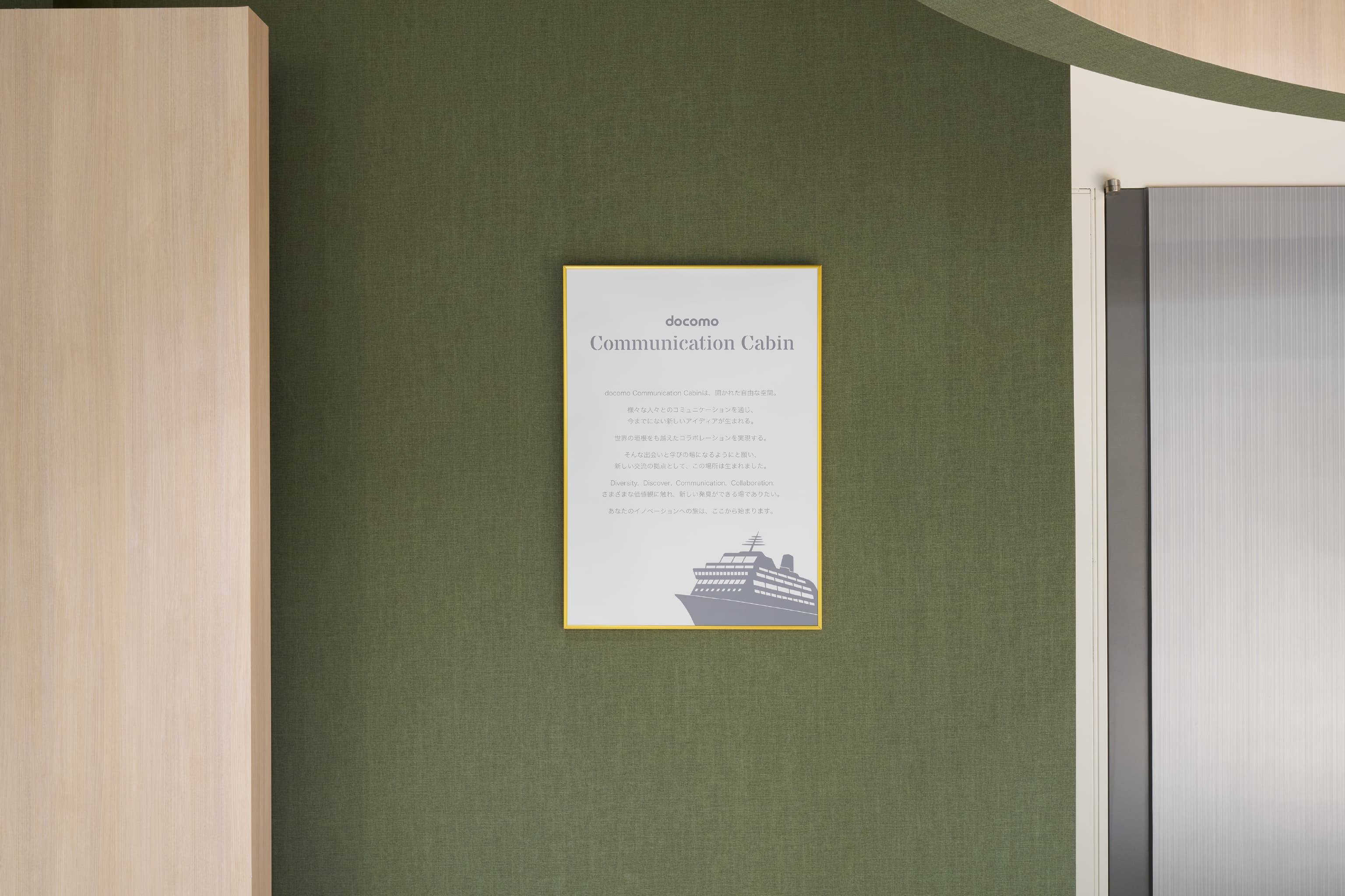 株式会社NTTドコモ 様の事例写真／[Rotary]入口に掲示されたパネルには、共創空間に込められた想いが綴られ、空間の意義を伝えています。穏やかな気持ちを誘うグリーンの壁も印象的。