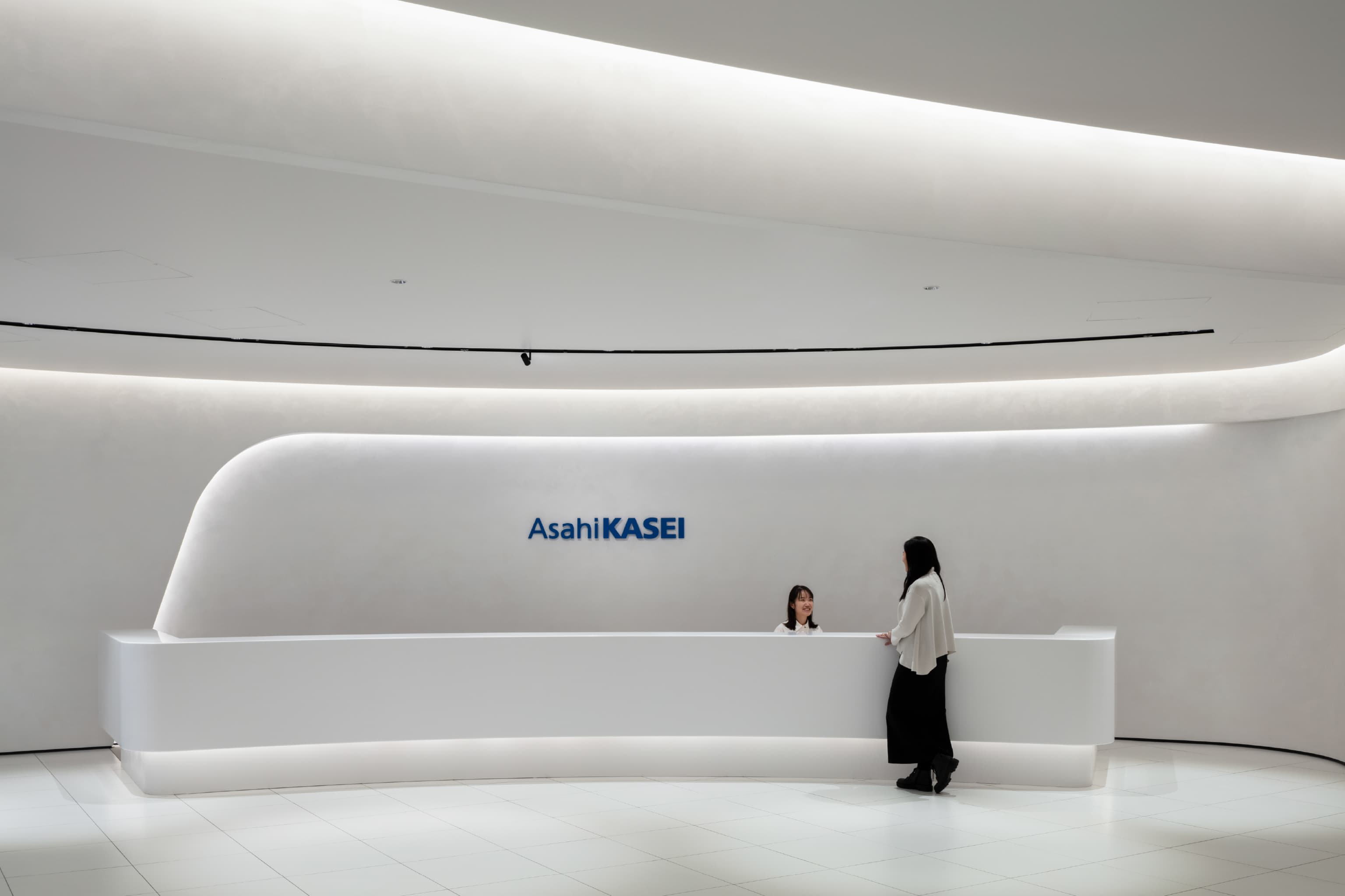 旭化成株式会社 様の事例写真／[受付]人が対応することで、「おもてなし」の気持ちが伝わります。受付カウンターにも曲線と白を基調としたデザインが施され、洗練された佇まいが信頼感と安心感を醸し出しています。