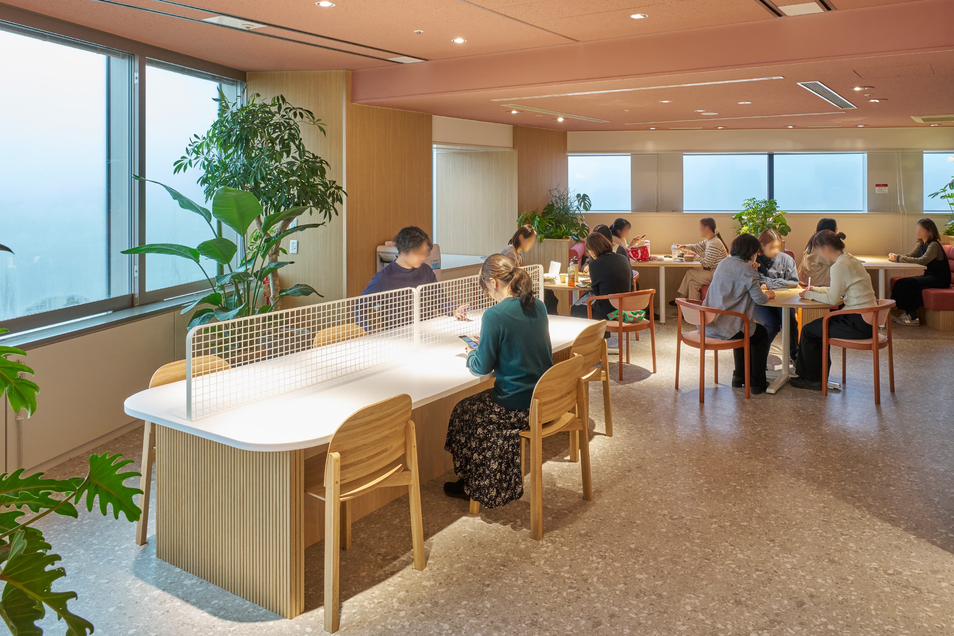 株式会社JALナビア 様の事例写真／[Chill Café]テーブルにはオープンエリア「Nexus」と連動するメッシュパネルが置かれ、対面に人が座っても視線が気になりません。写真奥の空間には可動式什器を採用し、人数に応じてフレキシブルに使える工夫が凝らされています。