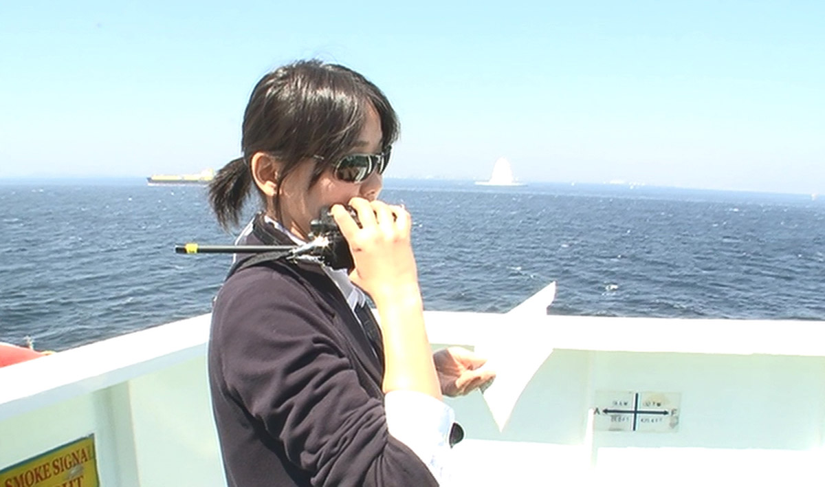 トランシーバーで指示を出す西川さん(画像:「若き海のパイロット」(日本水先人会連合会)より)