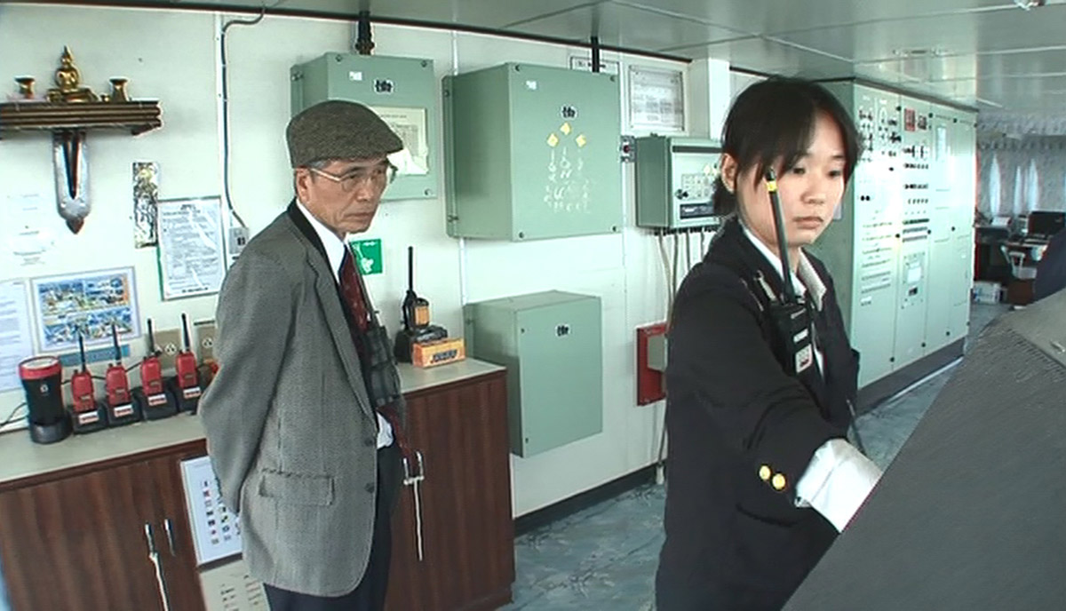 水先人になって１年目、指導水先人の監督下で水先業務を行う西川さん。後ろで指導水先人の目が厳しく光る（画像：「若き海のパイロット」（日本水先人会連合会）より）