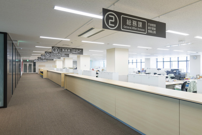 執務スペース／天吊りサインは天井レールで可動式、表示面はメンテナンスのしやすさに配慮している。