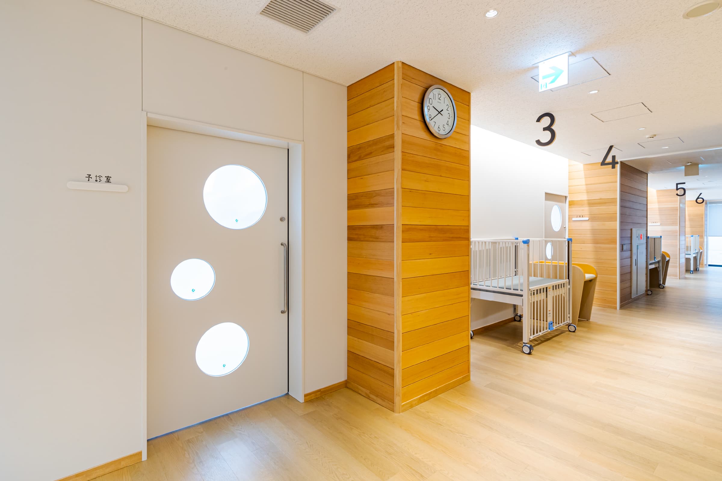 長崎健康相談所　廊下／予診室・診察室前には、休息や着替えなどができるよう、可動式ベットやおむつ交換台を複数配置。