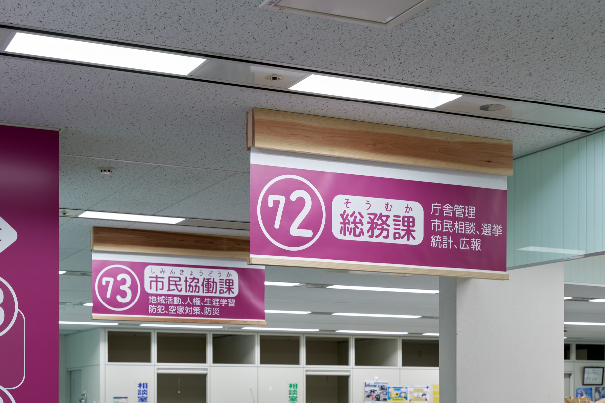 窓口サイン／奥まった場所に位置する窓口には、来庁者の動線から見えやすい箇所にサインを設置。吊元部分に国産木材を利用し、サインとしての統一感と温もりある空間演出。