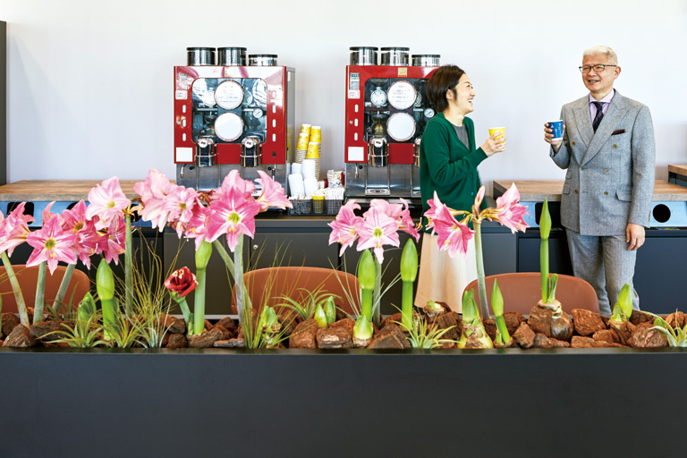 2行目：「REAL CAFE」では、球根から栽培し、成長を見守ったアマリリスの花が咲き始めている。常に挽きたてのコーヒーが楽しめることも、社員には好評である。